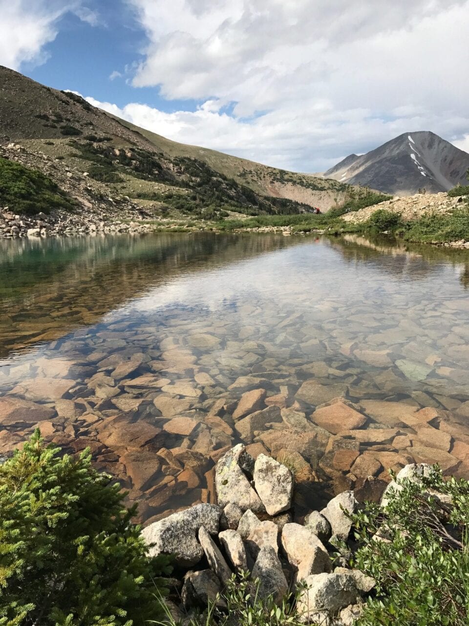 A view of a clear lake with a mountain in the background.