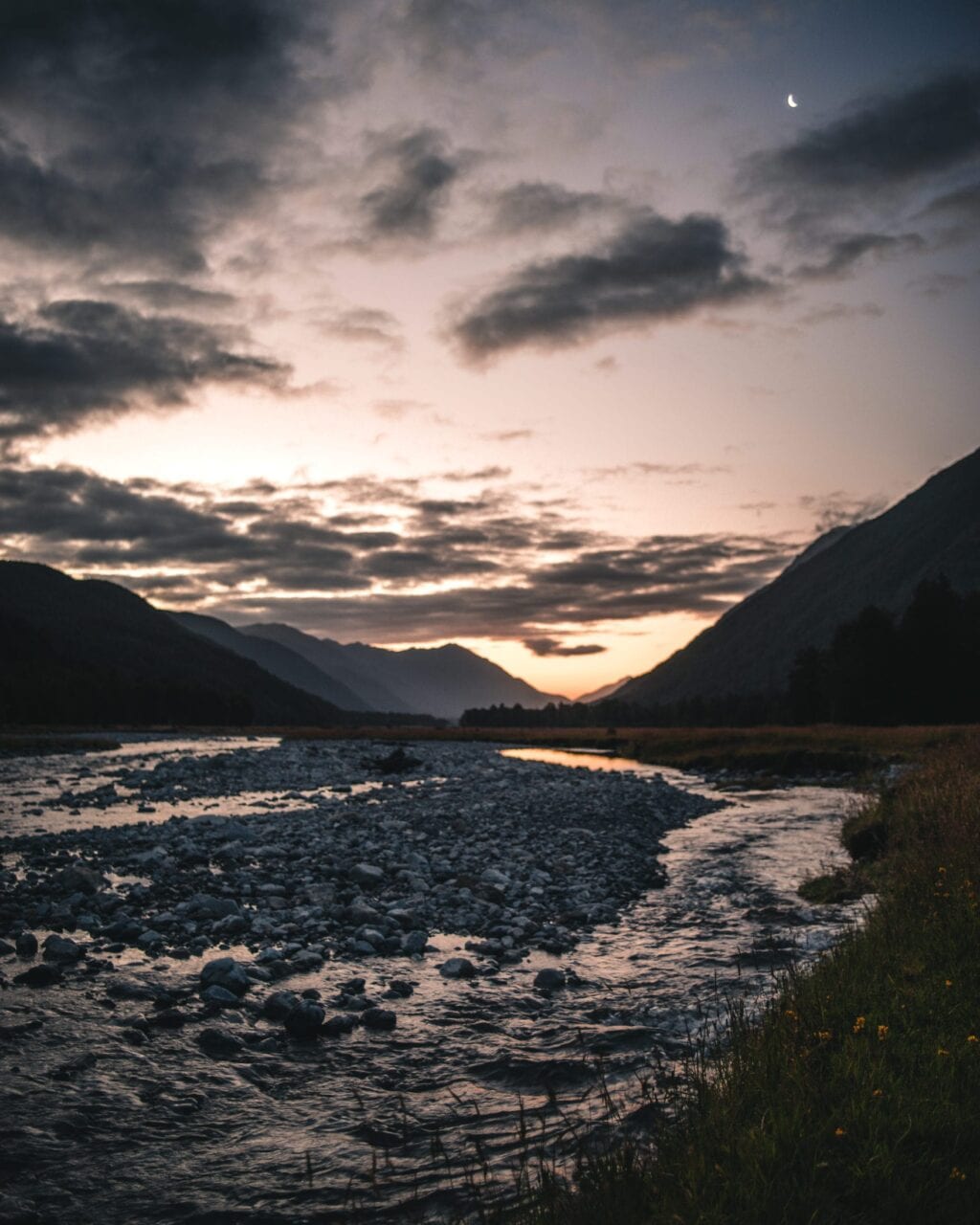 A sunset with mountains and a stream.
