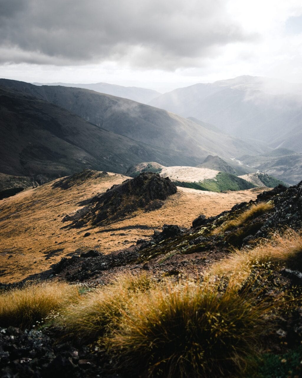 Sun shining through the clouds on a grassy mountain hill.