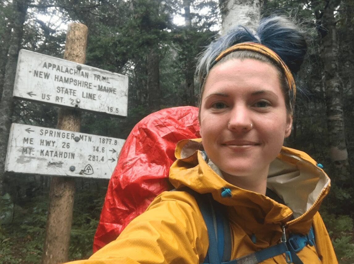 A woman in front of an Appalachian Trail sign.