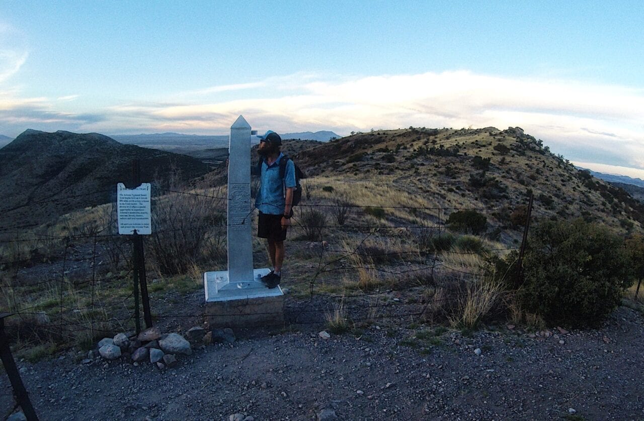 A hiker standing on the southern terminus of the Arizona Trail.