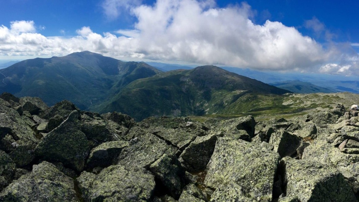 A ridge of rocky mountain peaks stretches into the distance against a blue sky.