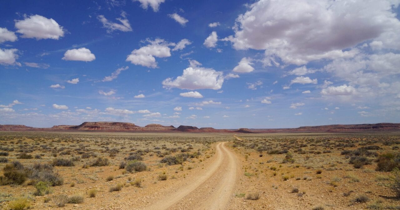 A jeep road extends through a desert landscape towards distant mountains on the Wild West Route.