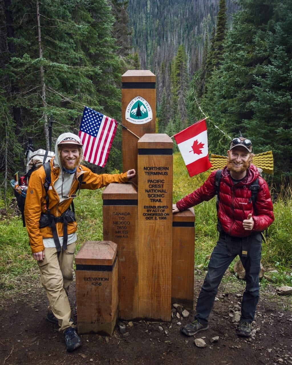 Two hikers standing next to the northern terminus of the Pacific Crest Trail.