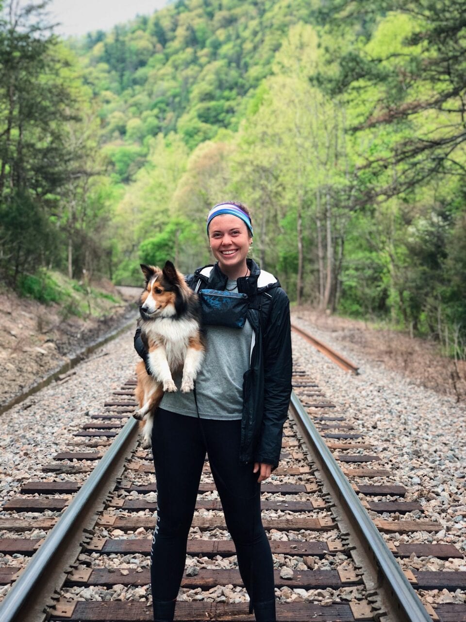 A girl holding her dog on the train tracks on the Appalachian Trail.