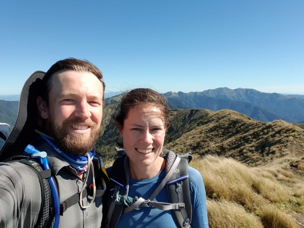 A man and woman smiling while hiking the Te Araroa.