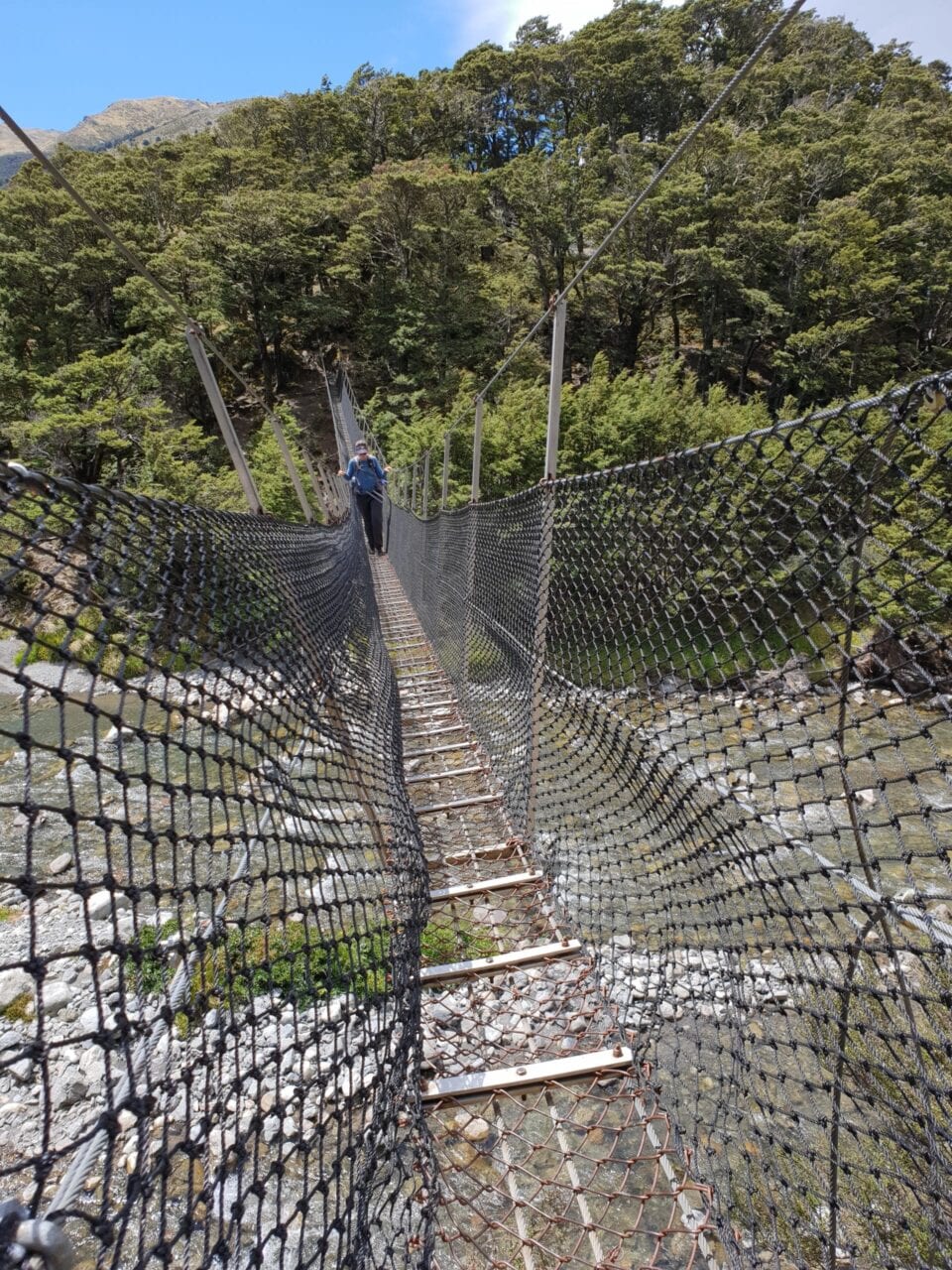 A hiker walking across a rope bridge on the Te Araroa.