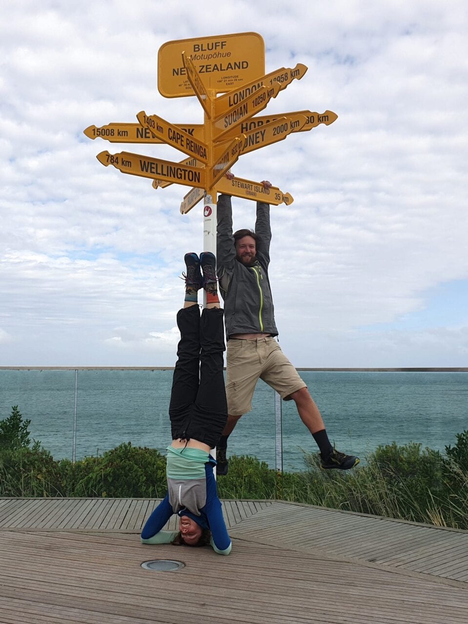 Two hikers posing next to the monument sign on the Te Araroa.