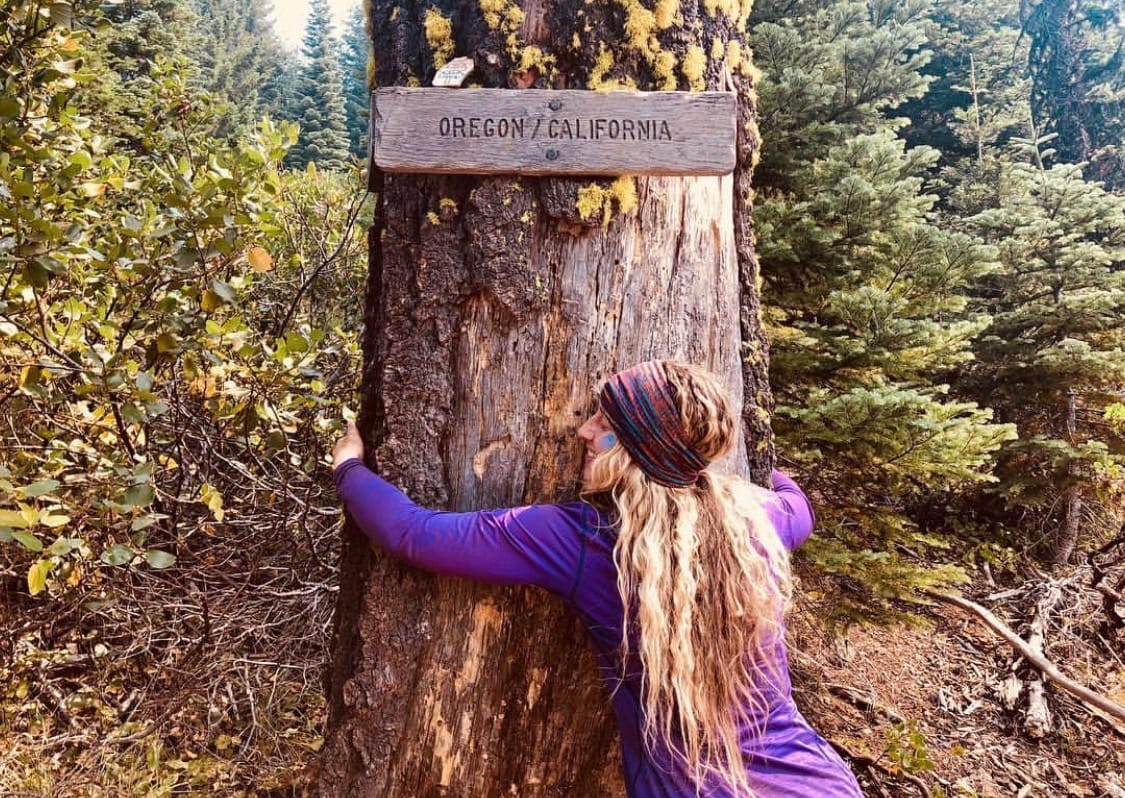 A woman hugging a tree.