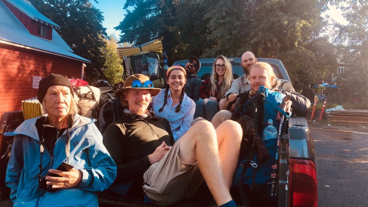 A group of hikers sitting in the back of a truck.