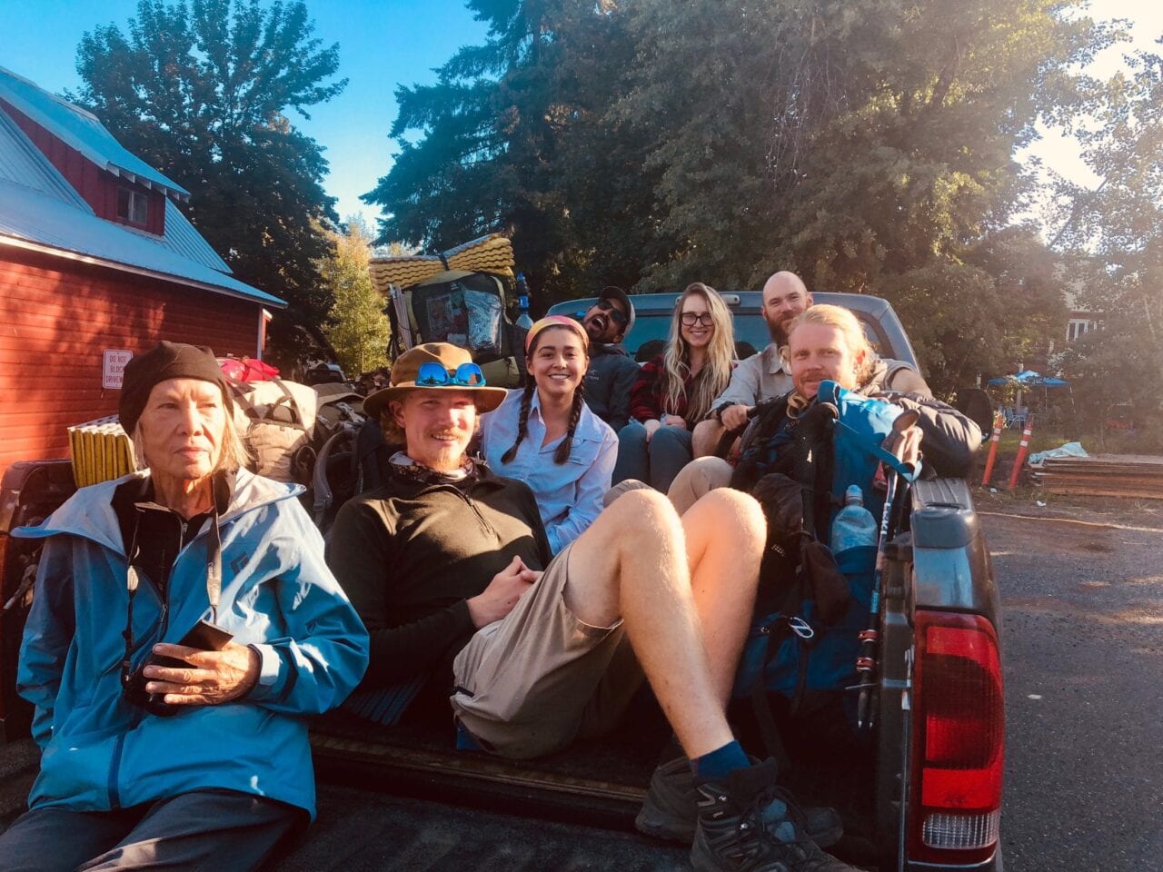 A group of hikers sitting in the back of a truck.