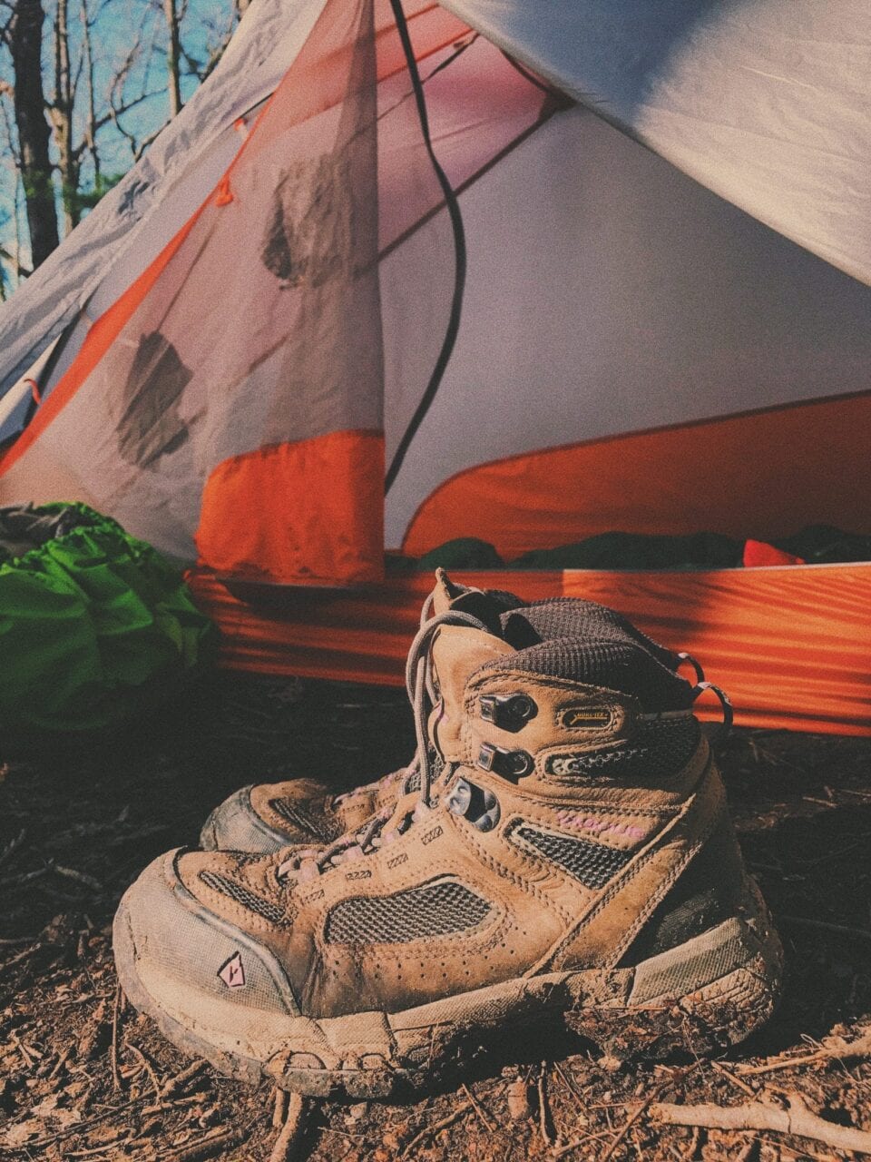 Hiking boots in front of a tent.