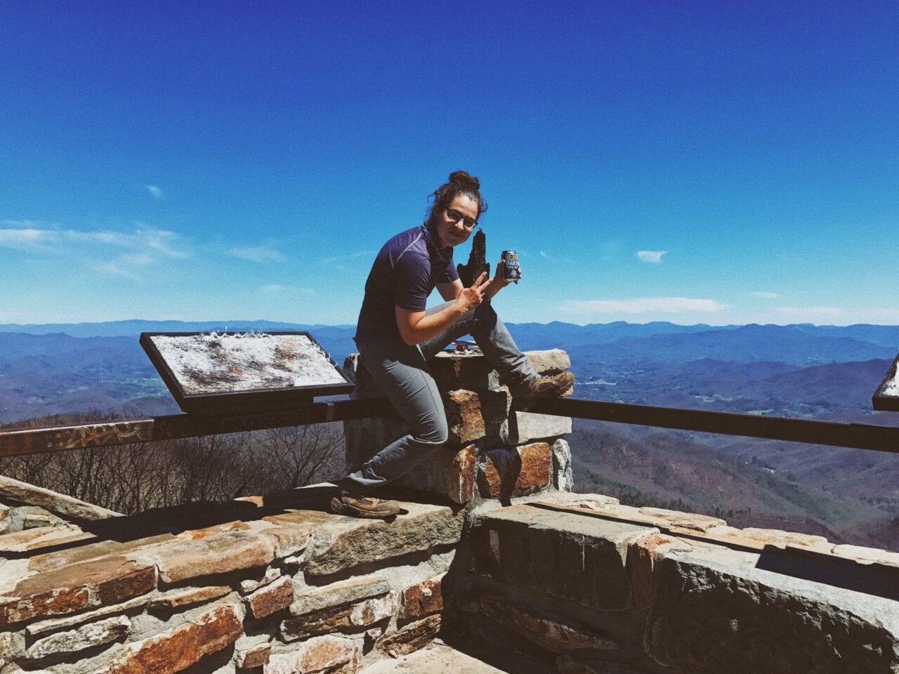 A hiker sitting on a lookout fence.