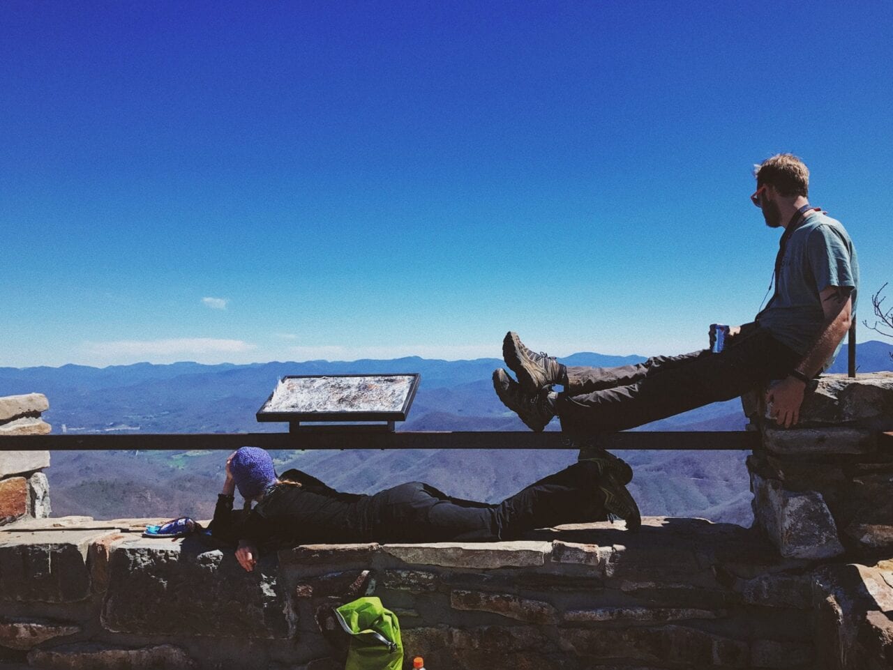 One hiker sitting and one hiker laying at a lookout on the Appalachian Trail.