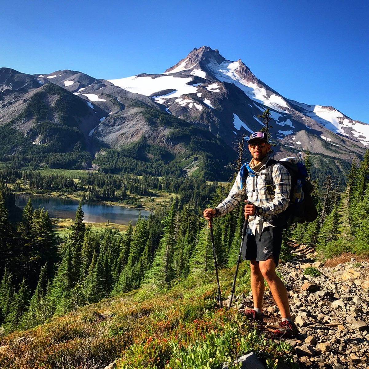 A hiker standing in front of a mountain on the Pacific Crest Trail.