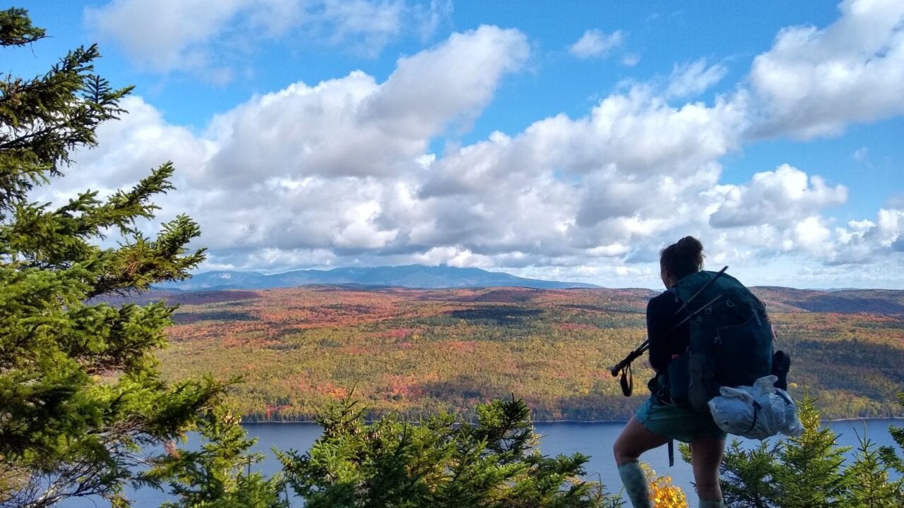 A hiker standing on a mountain looking out at a beautiful landscape.