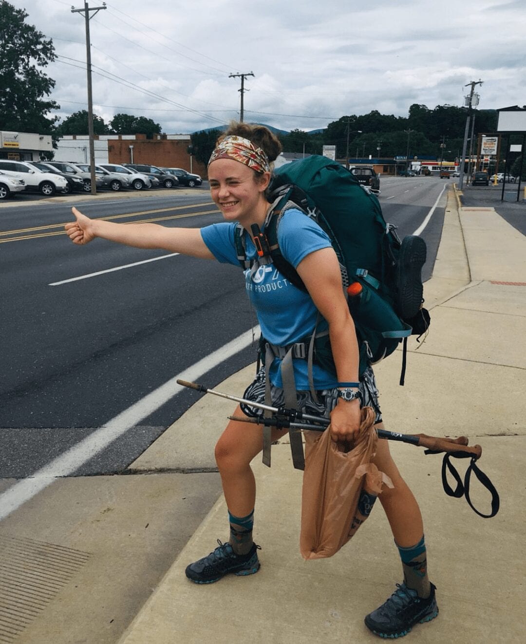 A thru-hiker is hitch-hiking on the side of the road.