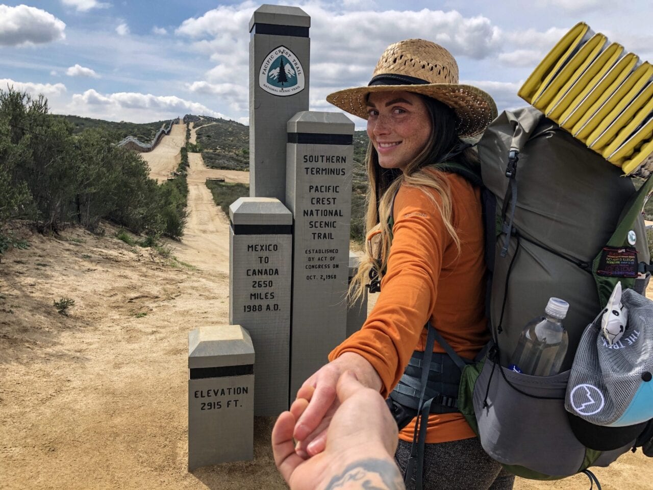 A woman holding a man's hand at the Southern Terminus of the PCT.