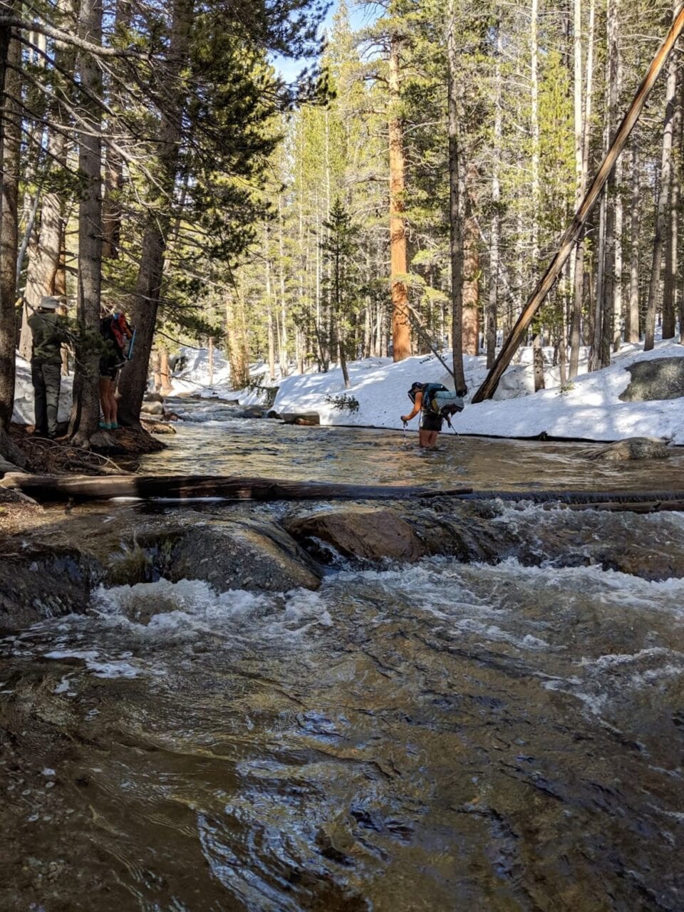 A hiker crossing a river.
