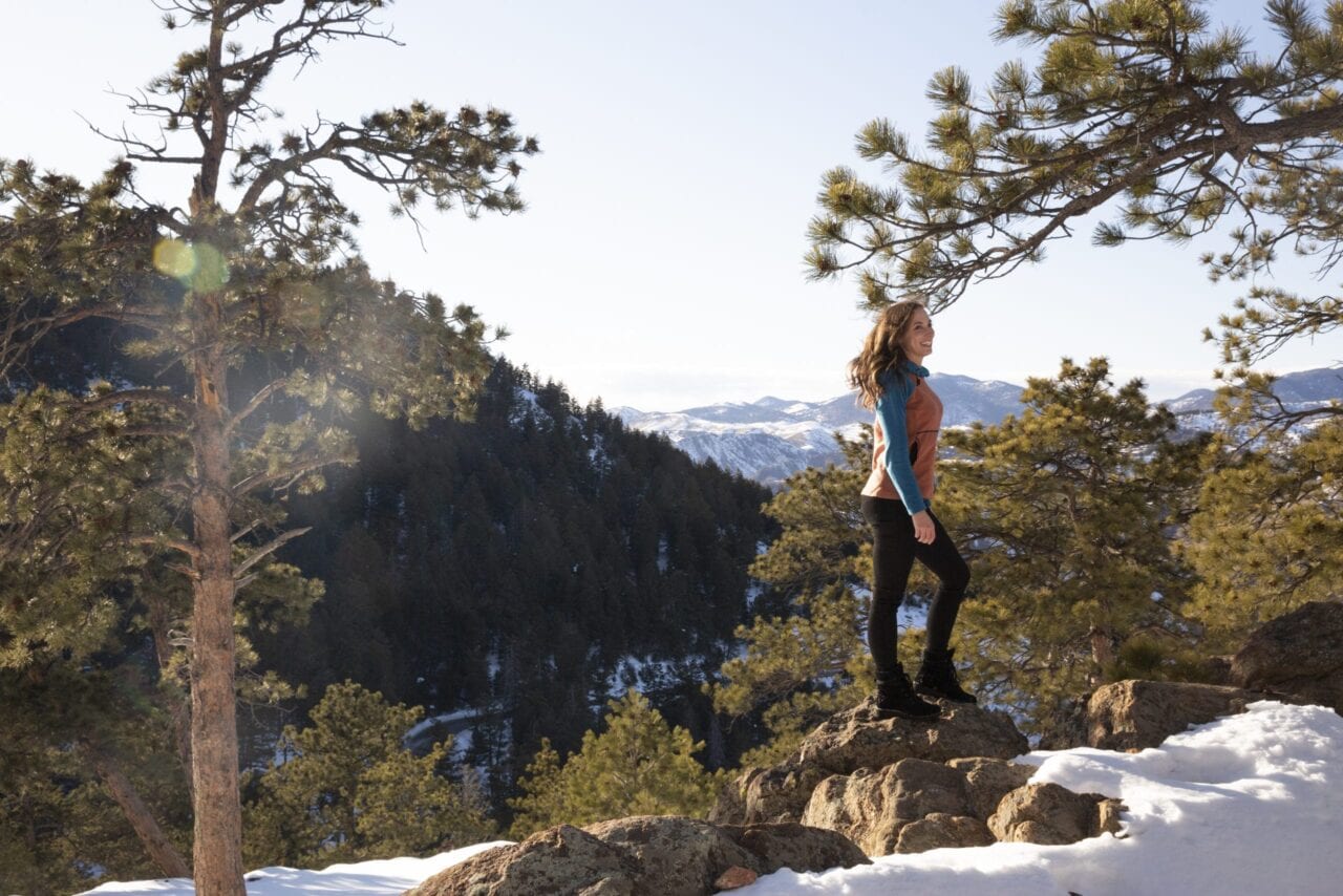 A woman standing on a hill in the snow covered mountains.