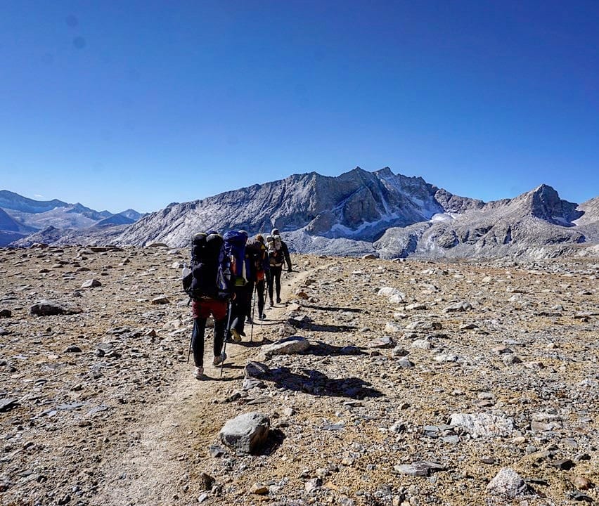A group of hikers in a line on a trail.