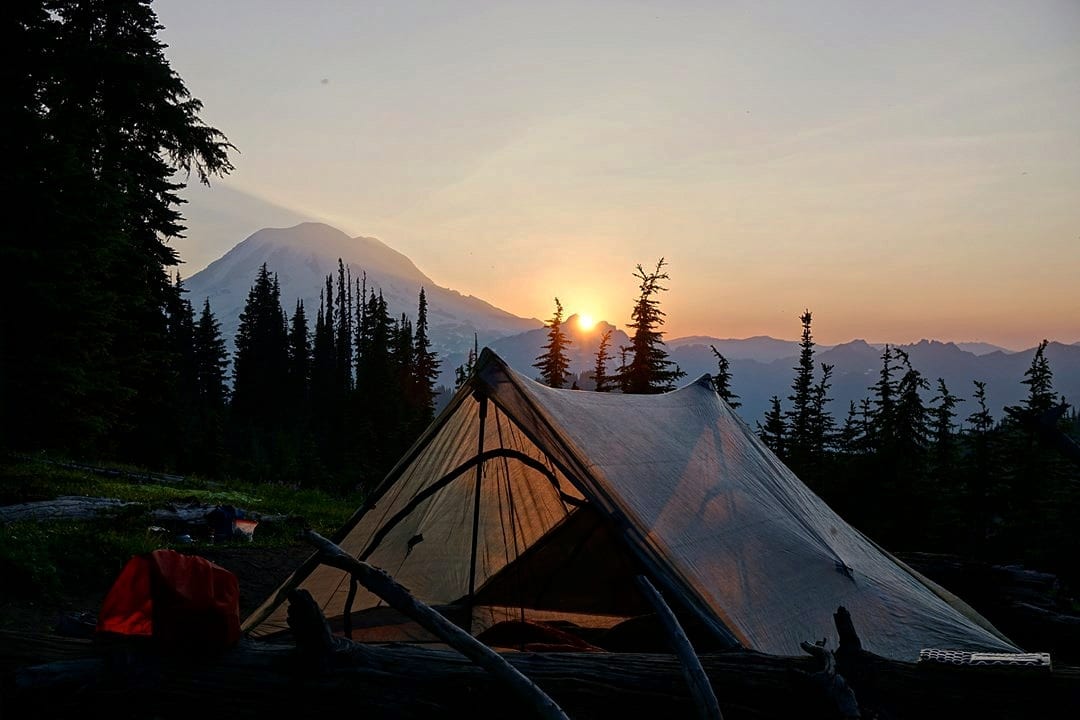 A tent with a sunset in the background.