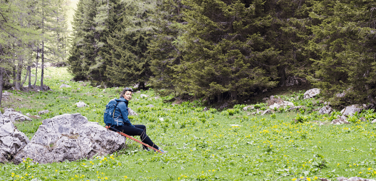 A woman sitting on a rock in the woods.