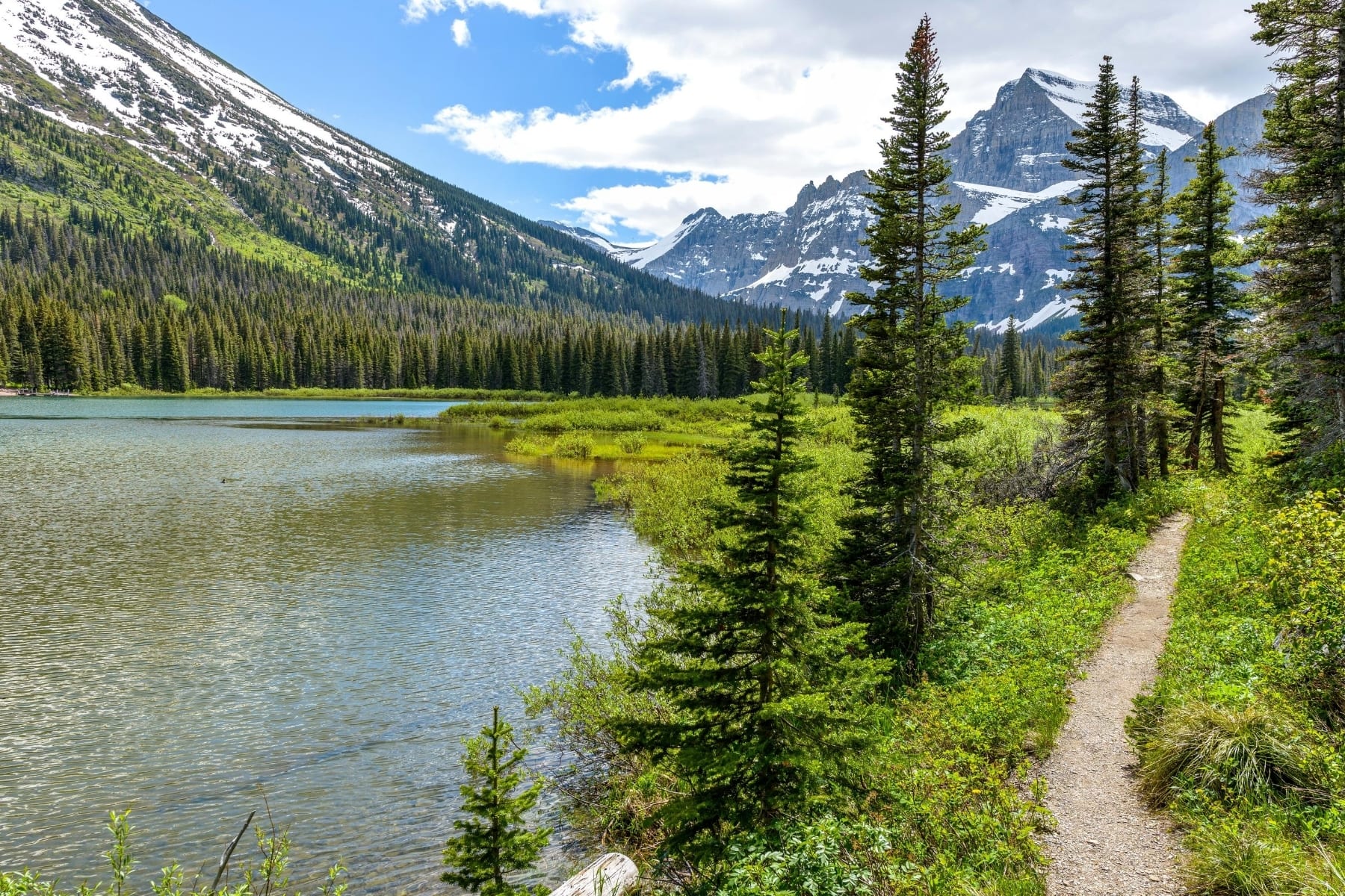 A trail next to a lake and some mountains.