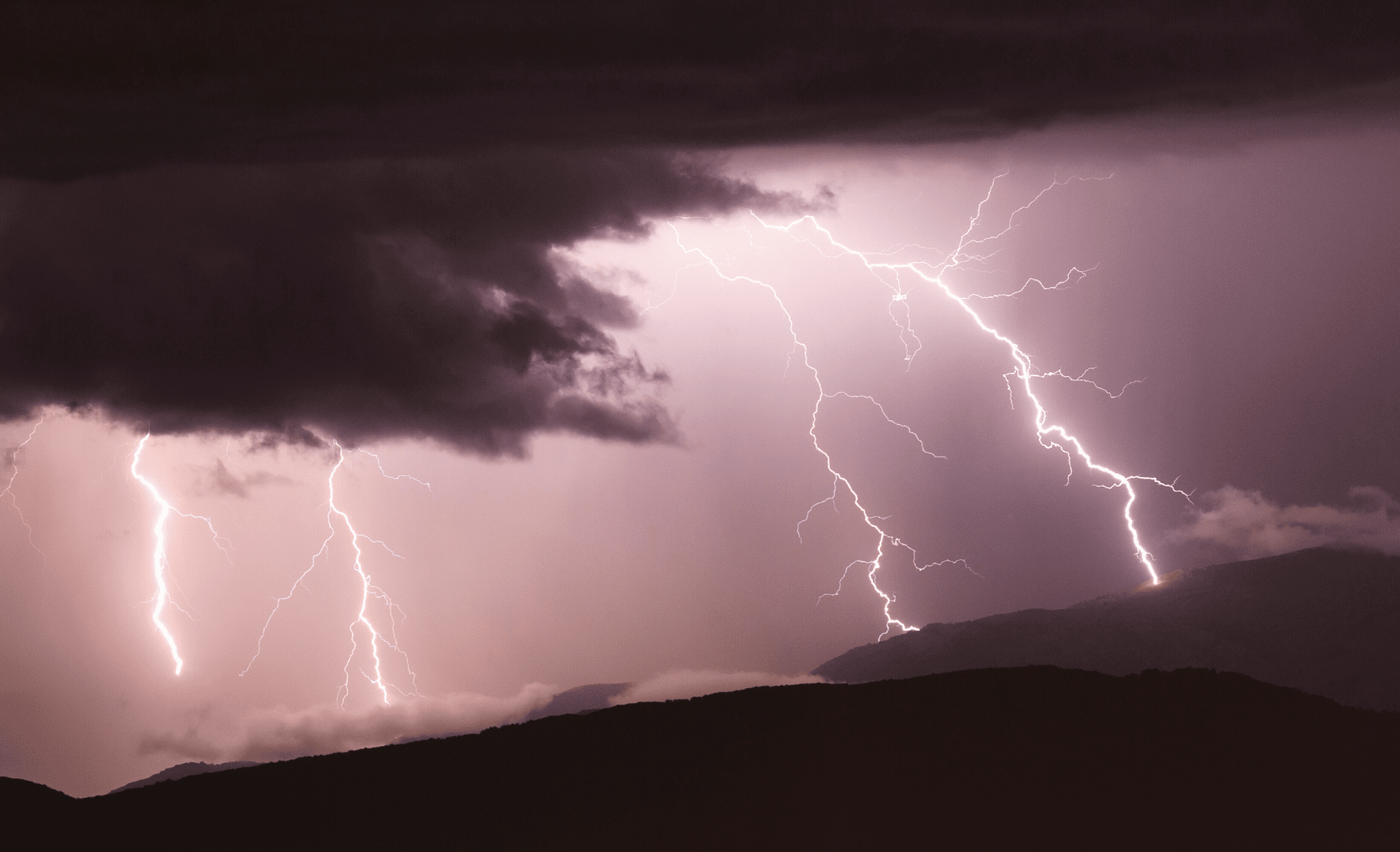 Four lightning strikes on a dark and flat mountain.