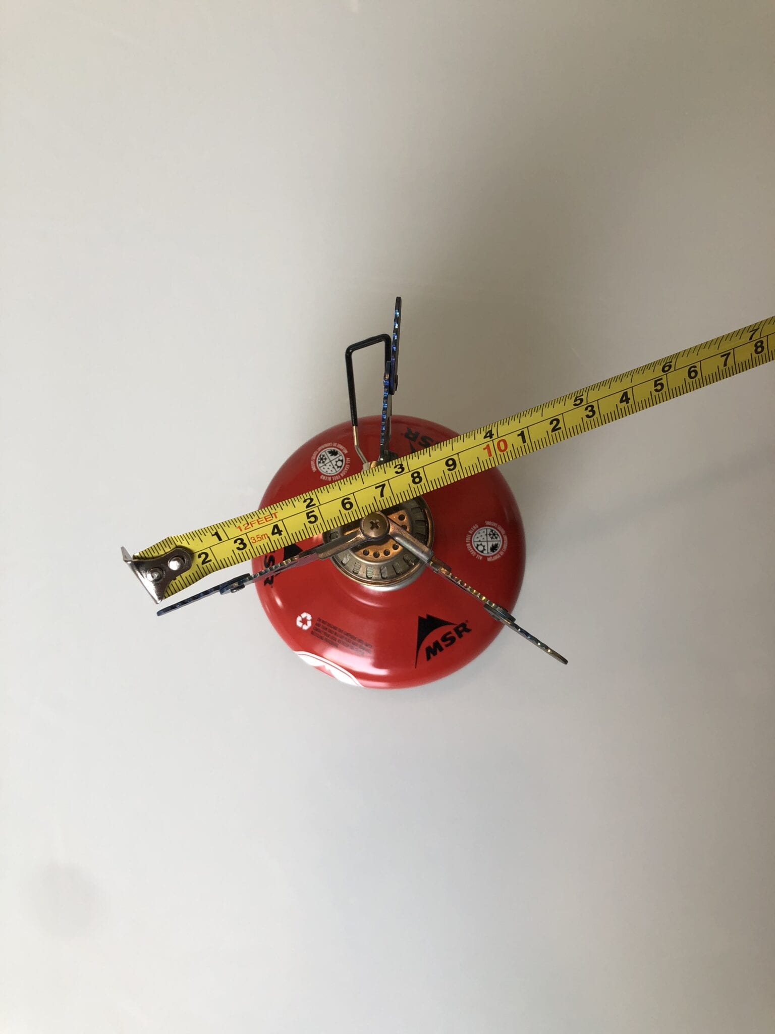 The Snow Peak LiteMax stove attached to a fuel canister being measured by a ruler.