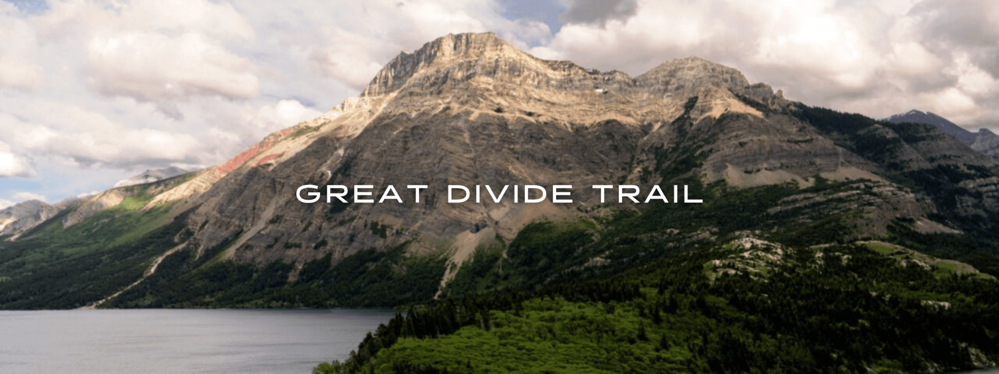 A view overlooks a lake, green forest, and rocky mountain.