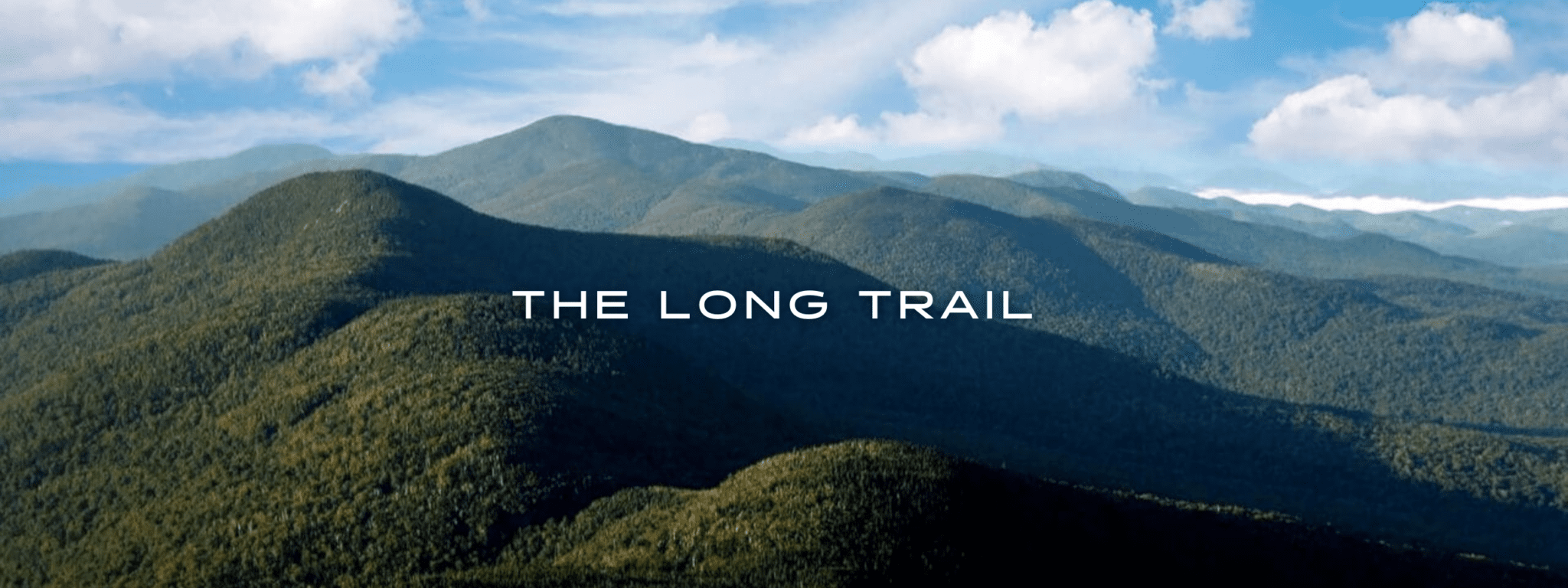 A view from The Long Trail at Mount Mansfield shows rolling green mountains in Vermont