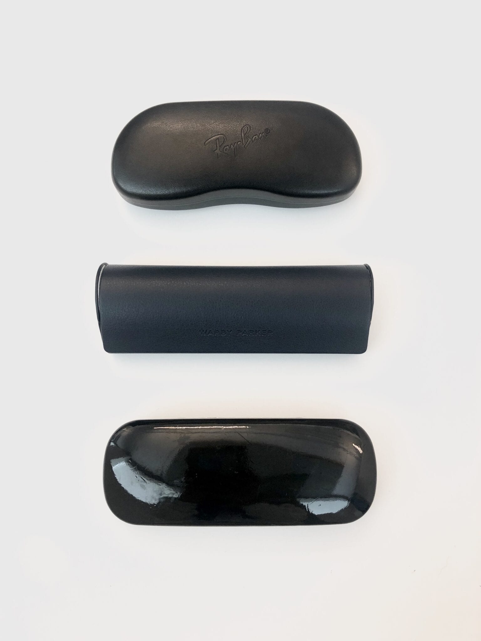 Three black glasses cases on a table.