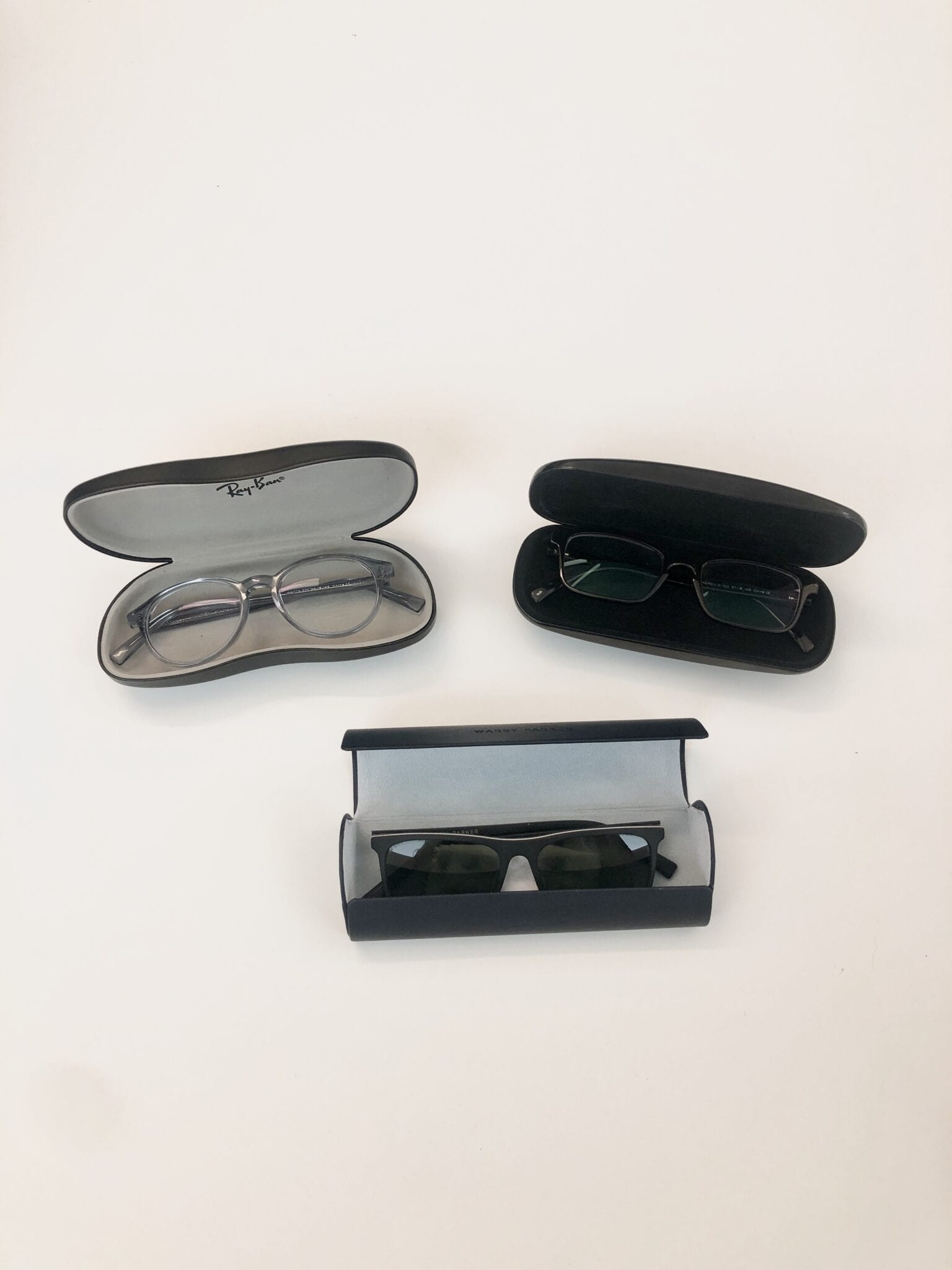 Three black glasses cases open with glasses in them on a table.