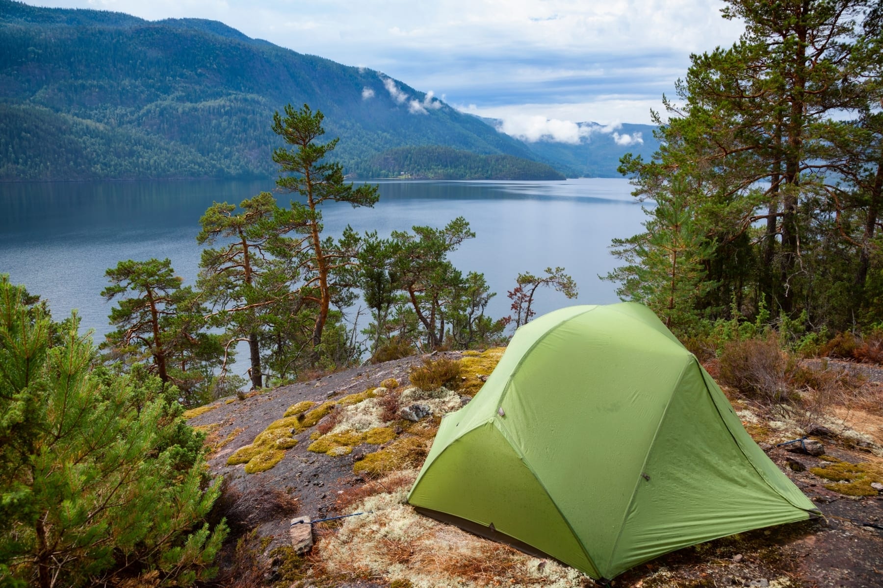 A green tent overlooking a lake and mountains
