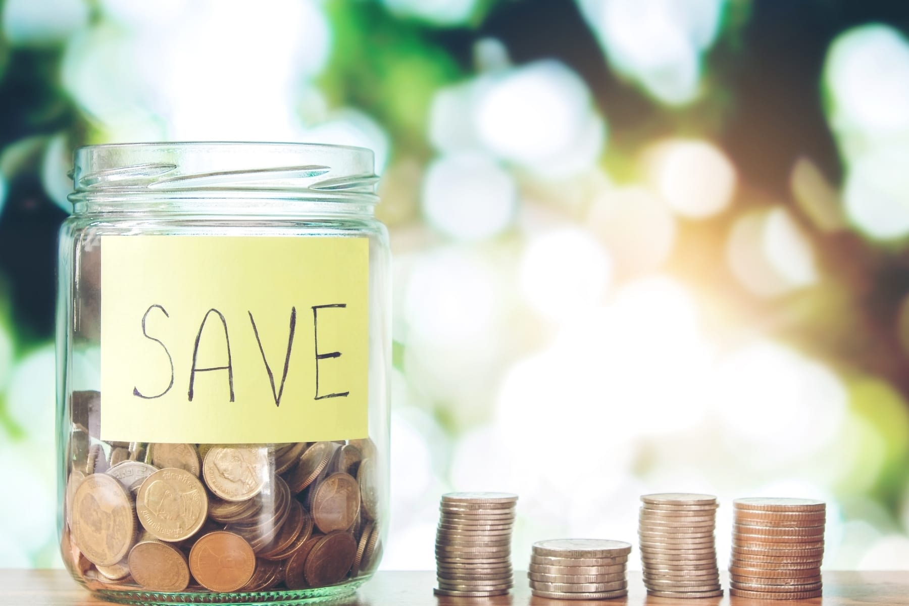 A savings glass jar with coins in it and next to it