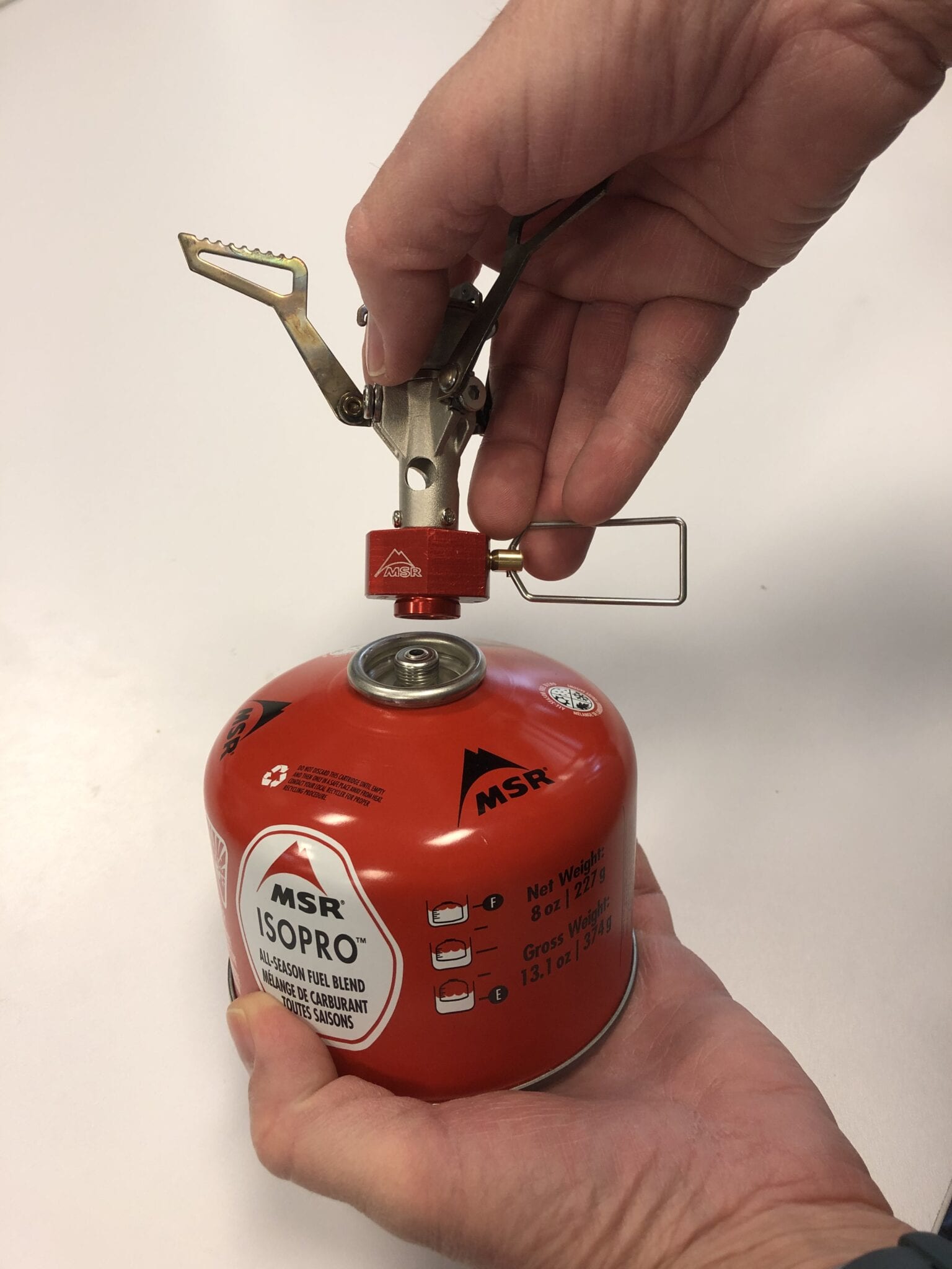 A backpacking stove being connected to a fuel canister.