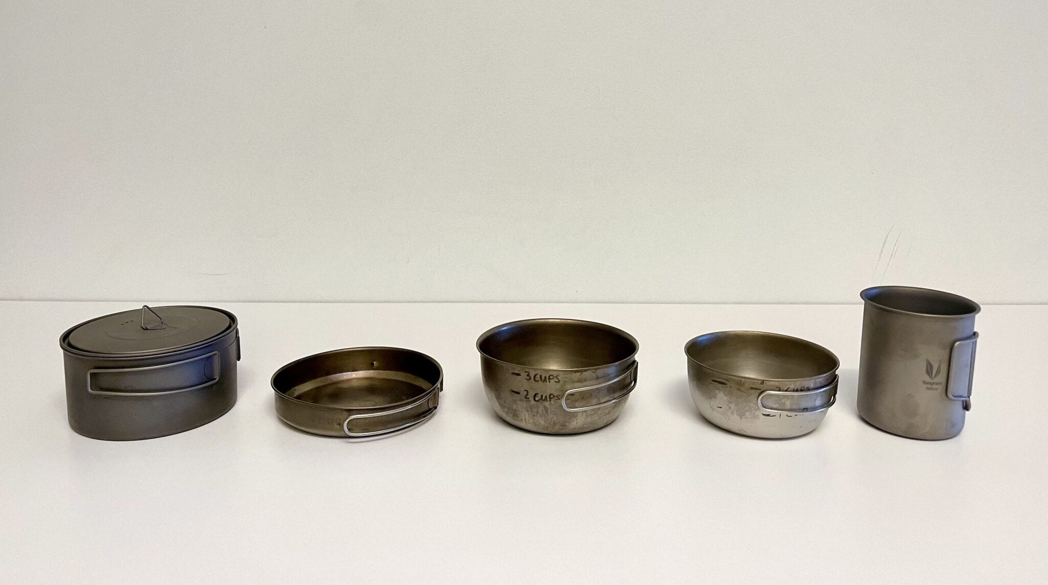 Five different sized backpacking cooking pots on a table.