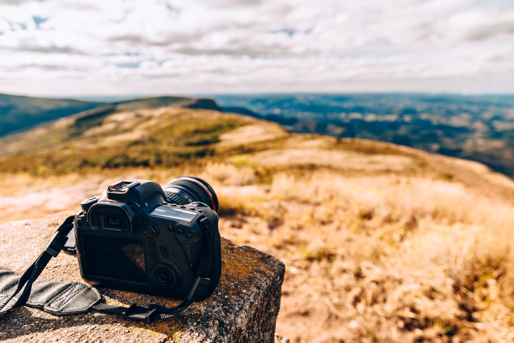 A DSLR camera on a rock outside.