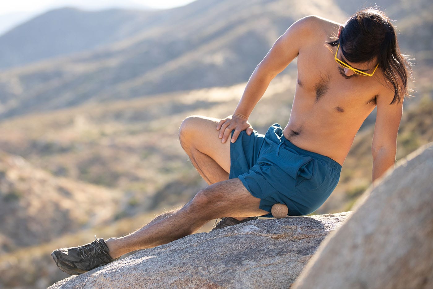 A man massaging his leg with a cork massage ball.