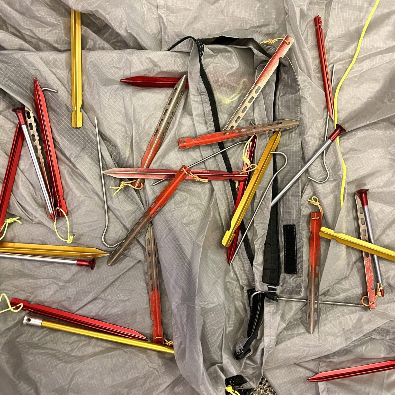 multiple different kinds of tent stakes laid out in a pile